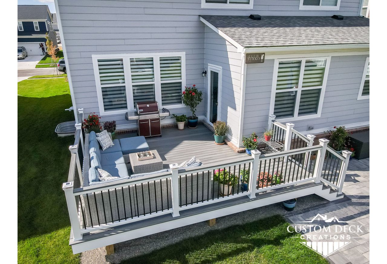 Trex Transcend Island Mist decking built with Trex Signature aluminum railing in black and white Trex composite railing posts. Matching cocktail board added to railing. Solar powered railing post cap lights.