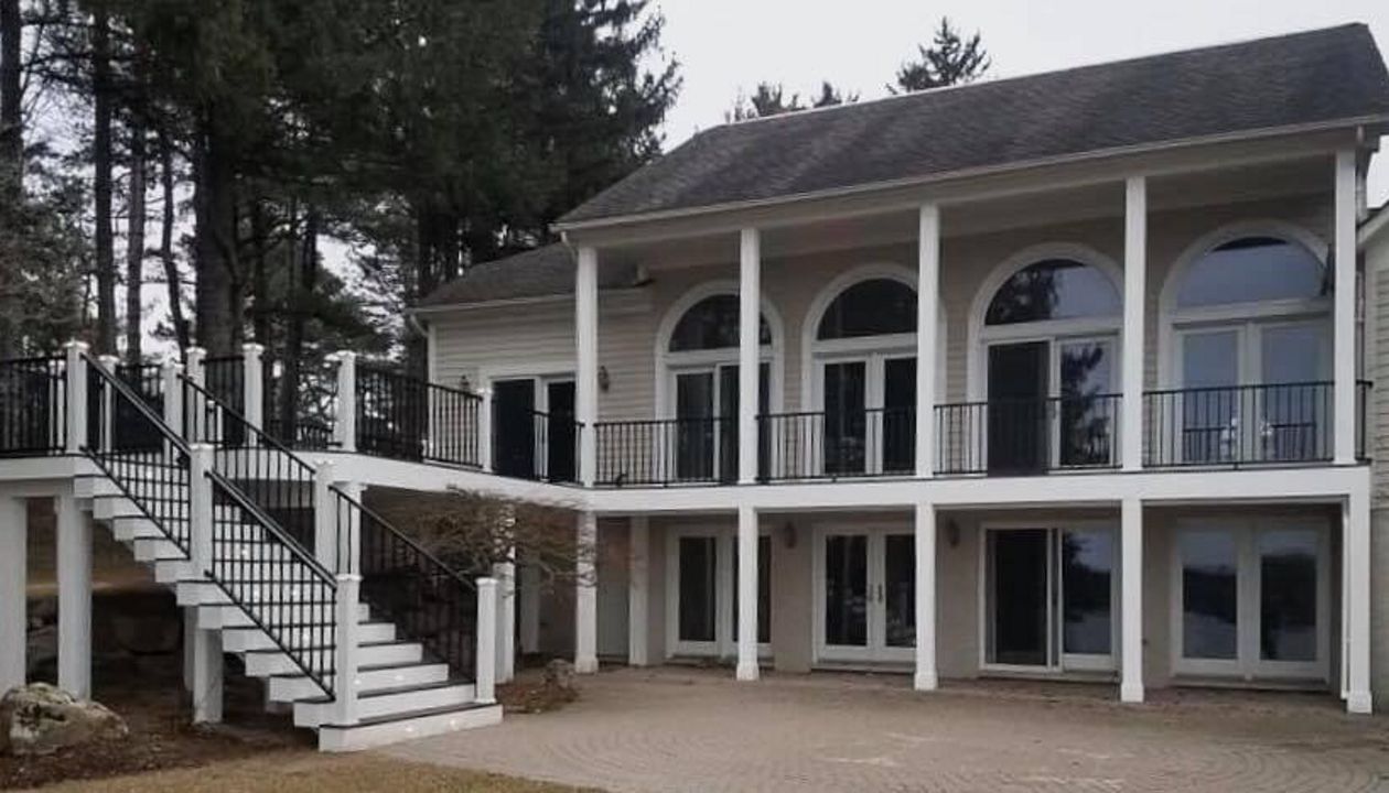 Vintage Lantern decking and border. Post Cap lights White fascia. Signature black rail with white posts. Footings wrapped. Waterford, Michigan