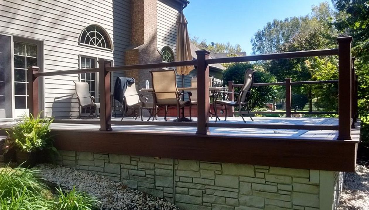 Glass panels in lieu of balusters complete this expanded deck in Island Lake, IL.  Transcend decking with a 2 tone look and we added PVC fence panels to enclose the underside of the deck for storage.