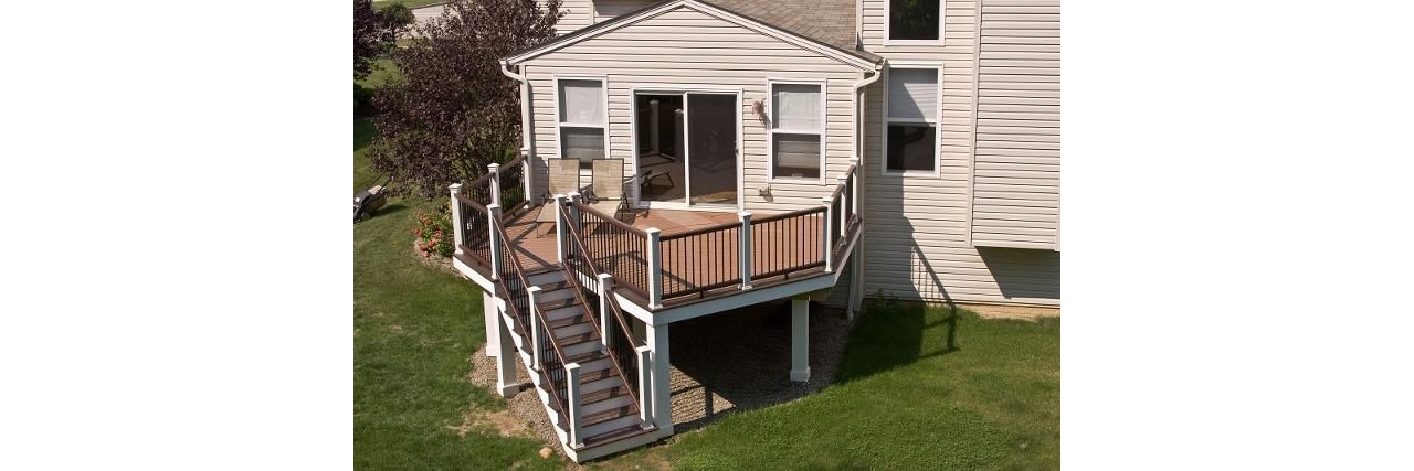 Elevated deck featuring Trex Enhance Beach Dune decking  with Vintage Lantern double boarder. The Trex Transcend Two-Tone Vintage Lantern railing and wrapped support columns sets this deck apart.
