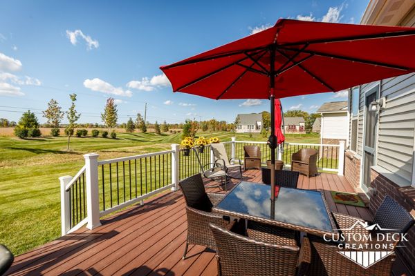 Trex Enhance Naturals Sunset Cove decking with matching parting board. Railing is Trex Select composite railing in white with black round aluminum balusters.