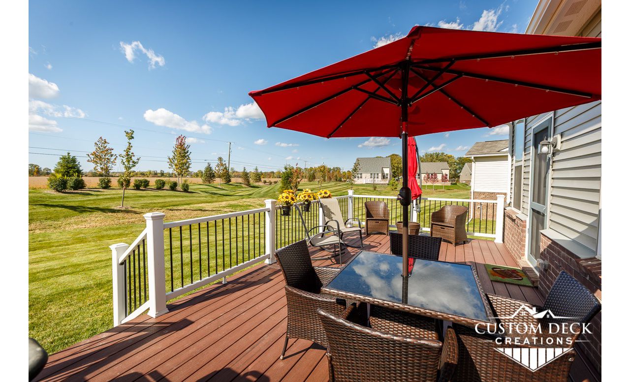 Trex Enhance Naturals Sunset Cove decking with matching parting board. Railing is Trex Select composite railing in white with black round aluminum balusters.