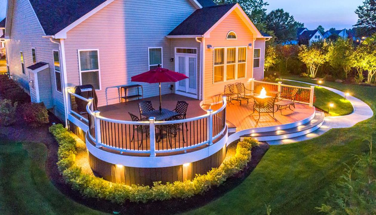Custom Curved Trex Transcend deck in Tree House with white Trex Trascend railing with aluminum balusters. Trex Low voltage LED cap lights