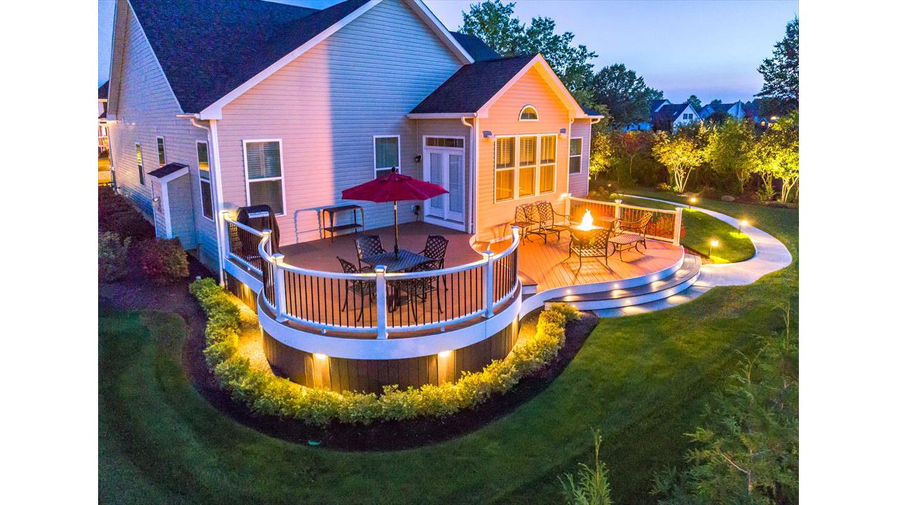 Custom Curved Trex Transcend deck in Tree House with white Trex Trascend railing with aluminum balusters. Trex Low voltage LED cap lights