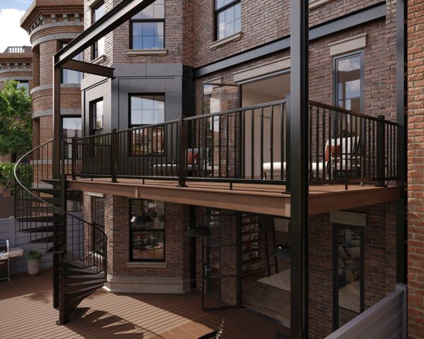 A contemporary balcony with a black metal railing and spiral staircase is attached to a classic brick apartment building. The setting features large windows, outdoor seating, and a spacious wooden deck below. The scene is well-lit with natural daylight, highlighting the contrast between modern metalwork and historic architecture. No visible text or numbers are present in the image.