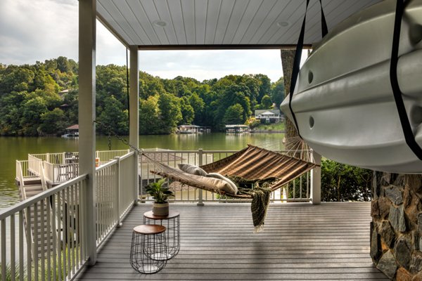 Lakeside deck with hammock, side tables, and kayak with dock house in the distance