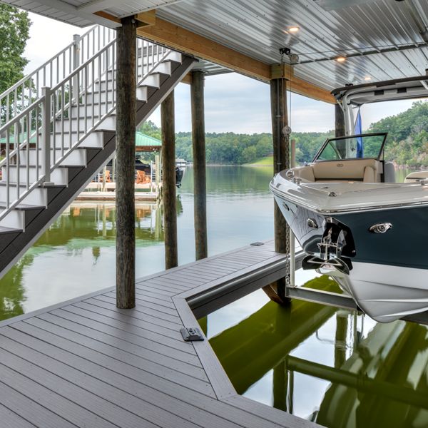 12. A dock made of Trex decking with it cut to allow a boat to dock under a covering. A staircase connects to the dock and leads to a higher level deck made of Trex decking in the color Whidbey.