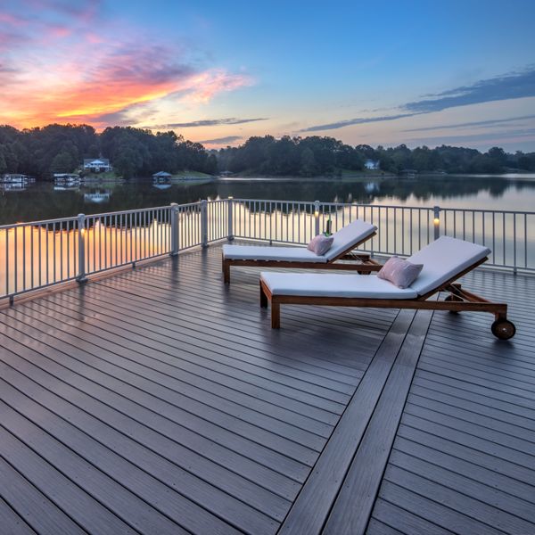 11. A dock on the water made with Trex Signature decking with Trex Signature railing accenting the deck, while the sunsets over the greenery in the background.