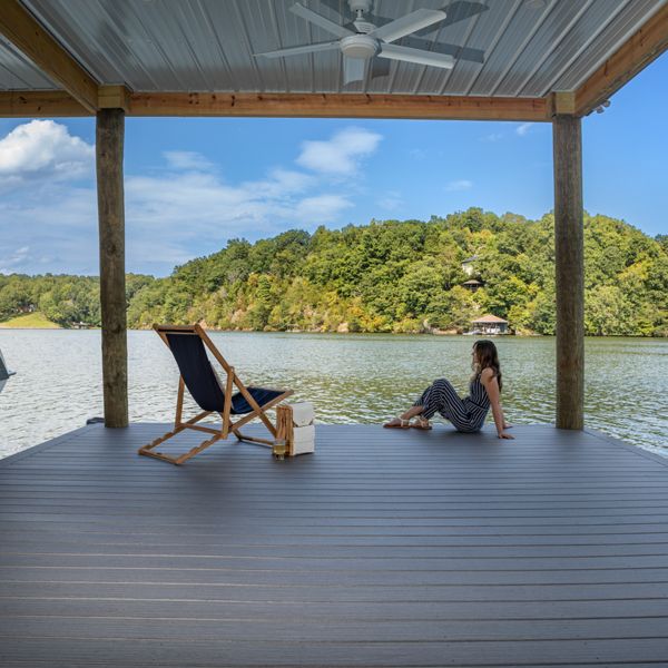 13. Woman sitting on a dock made of Trex decking, with the water behind her.