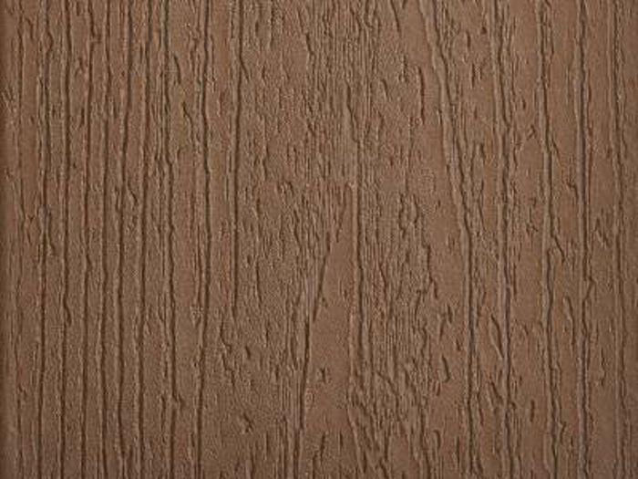 A close-up view of a brown wood grain texture is shown, highlighting the natural lines and grooves typical of wooden surfaces. The image focuses on the tactile details, with vertical striations and subtle color variations. The setting is neutral, emphasizing the material's organic appearance and earthy tone. No visible text, numbers, or identifiable brands are present.