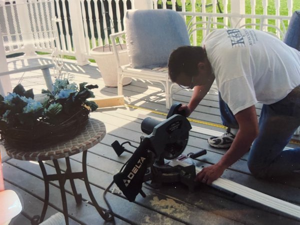 A man installing Trex decking on a front porch.