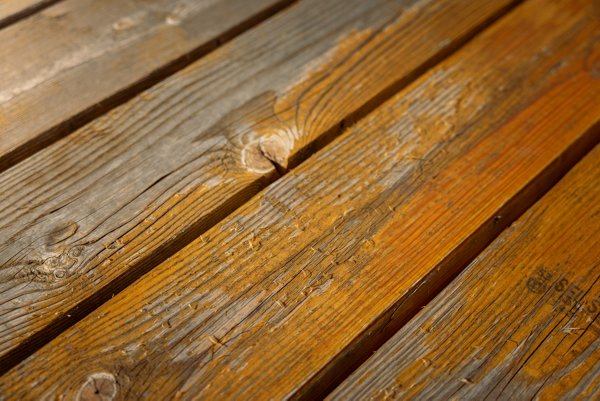 A close up of wood boards with bad stains and splinters visible on the surface. 