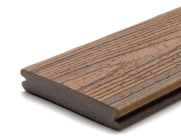 A single brown composite decking board is shown against a white background. The board features a realistic wood grain texture on its surface, mimicking the appearance of natural wood. The edges are grooved, suggesting suitability for hidden fastener installation. The image highlights the material's durability and modern construction. No visible text, numbers, or logos are present.