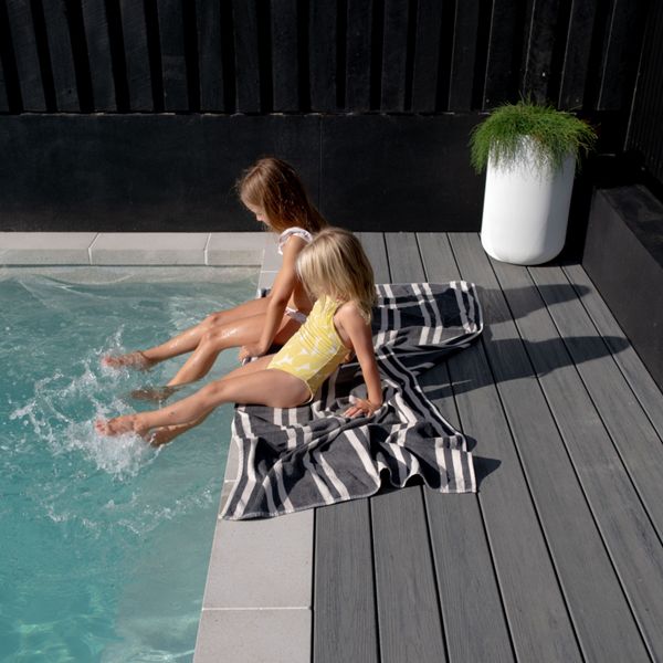 Children playing in a pool with an Island Mist Trex deck around the pool.