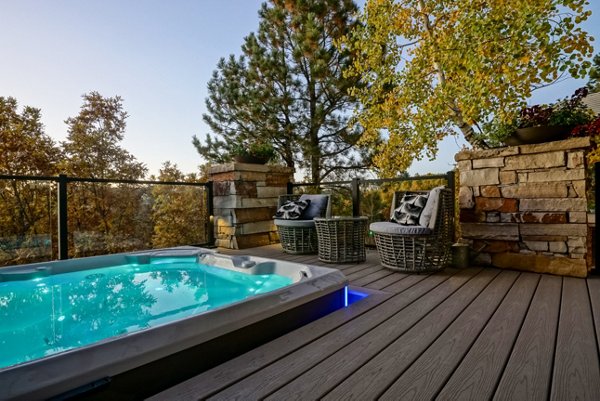 Hot tub built into a grey composite deck with glass railings in the background