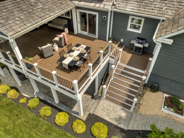 Home with a large deck with a cocktail railing and classic stairs leading to a garden below.