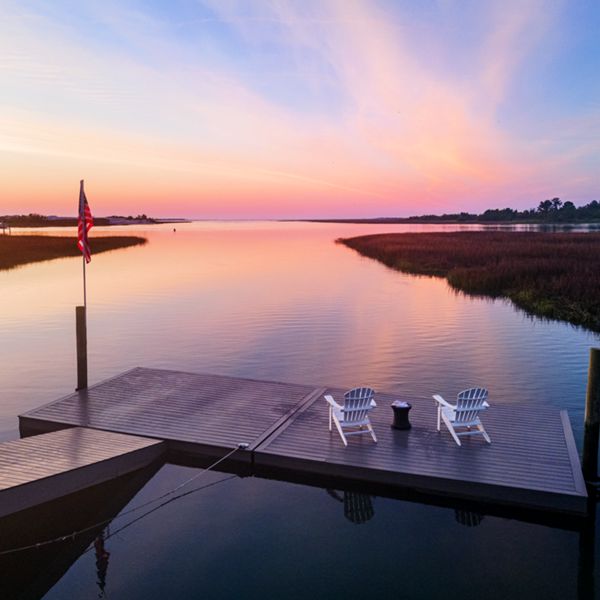 5. Two chairs sitting on a dock made of Trex decking with a gorgeous sunset illuminating the water. 