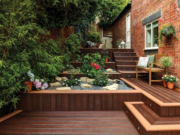 Small outdoor garden deck with deck stairs leading up to another level.