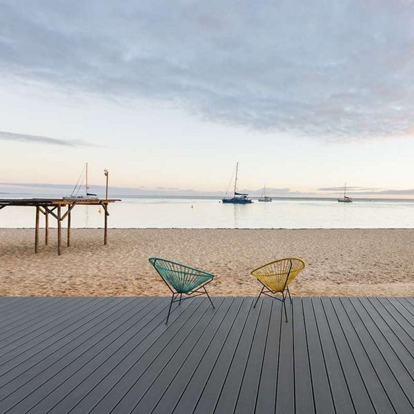 3. Two chairs on a Trex boardwalk facing the beach with the beginnings of sunset in the distance.